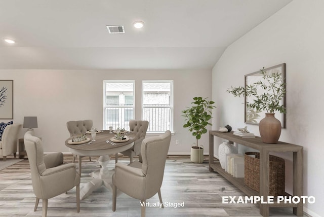 dining area featuring visible vents, light wood-style flooring, baseboards, and lofted ceiling