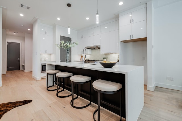 1609 Park St, Houston, TX 77019 - kitchen with under cabinet range hood, backsplash, white cabinets, light countertops, and recessed lighting