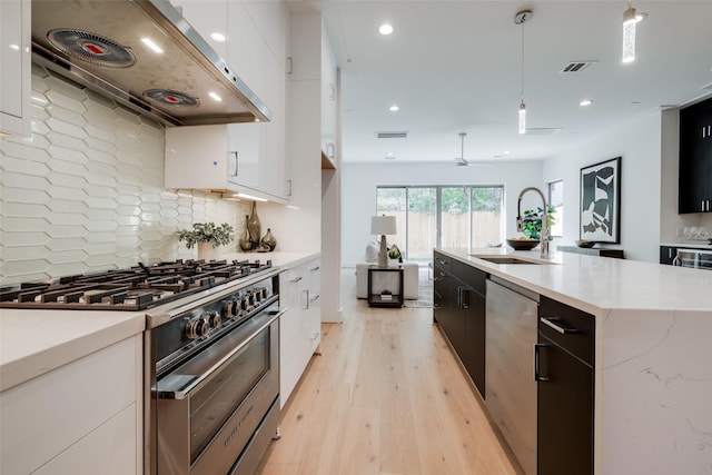 1609 Park St, Houston, TX 77019 - kitchen with appliances with stainless steel finishes, range hood, decorative backsplash, white cabinetry, and decorative light fixtures