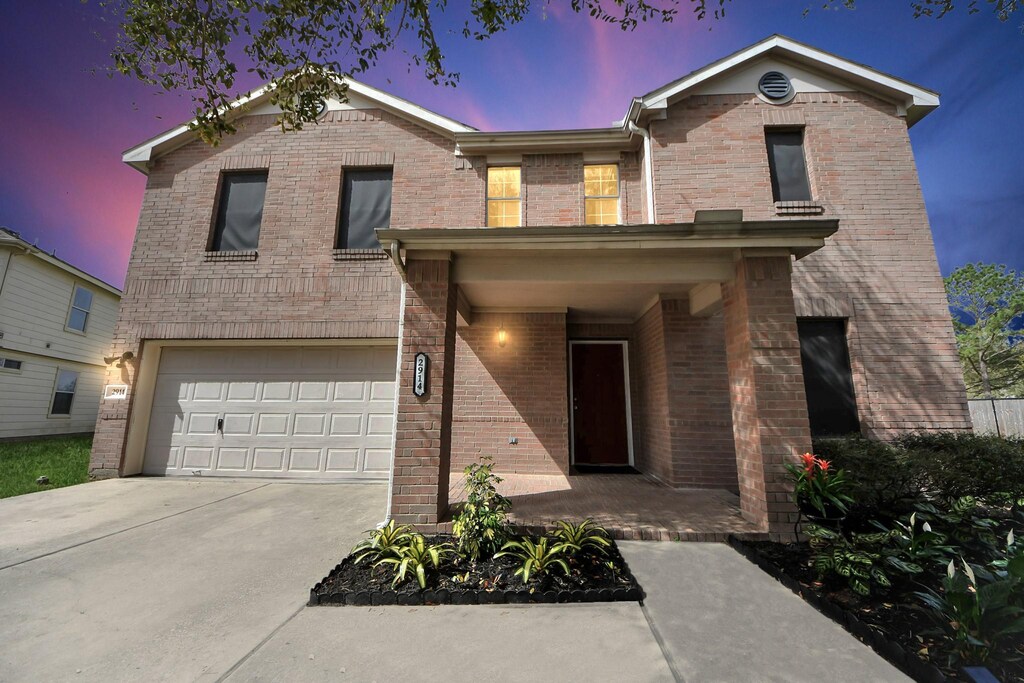 view of front of home with brick siding, a garage, and driveway