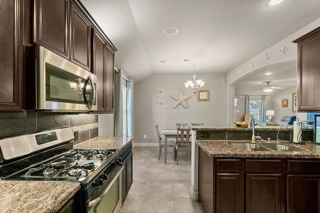 kitchen with dark stone counters, a sink, appliances with stainless steel finishes, ceiling fan with notable chandelier, and backsplash