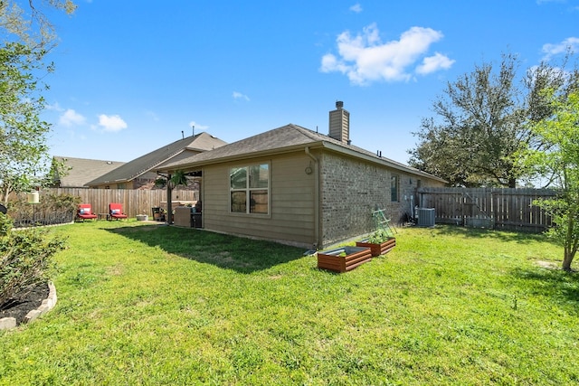 rear view of property with a lawn, cooling unit, a chimney, and a fenced backyard