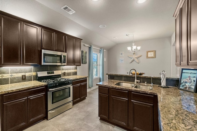 kitchen featuring visible vents, a peninsula, a sink, stainless steel appliances, and tasteful backsplash