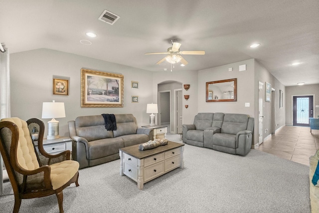 living area with visible vents, light colored carpet, light tile patterned floors, arched walkways, and a ceiling fan