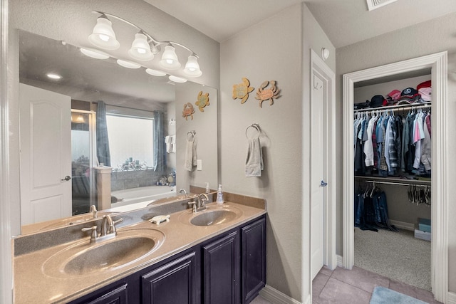 full bathroom with a sink, a walk in closet, double vanity, and tile patterned flooring