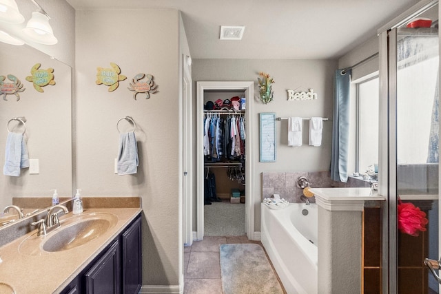 bathroom featuring a walk in closet, visible vents, a garden tub, tile patterned flooring, and vanity