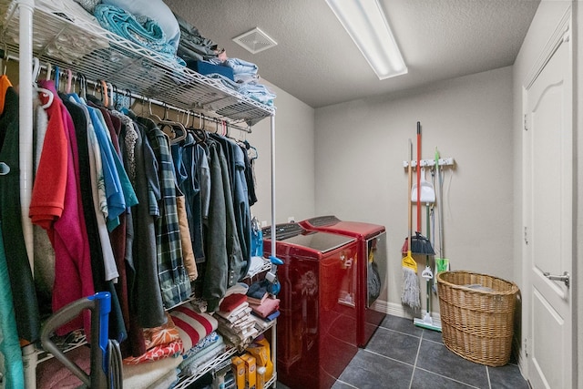 clothes washing area with visible vents, dark tile patterned floors, laundry area, washer and dryer, and a textured ceiling