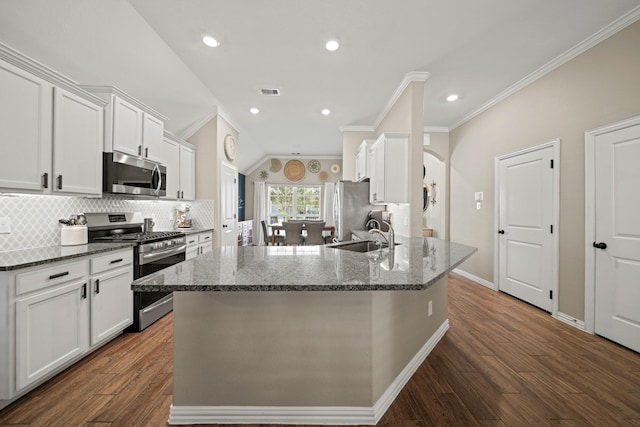 kitchen featuring a sink, stainless steel appliances, arched walkways, white cabinets, and decorative backsplash