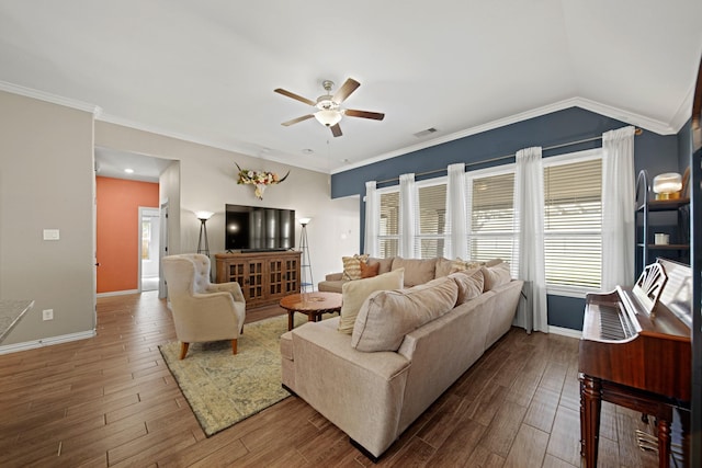 living area with wood finished floors, baseboards, ornamental molding, ceiling fan, and vaulted ceiling