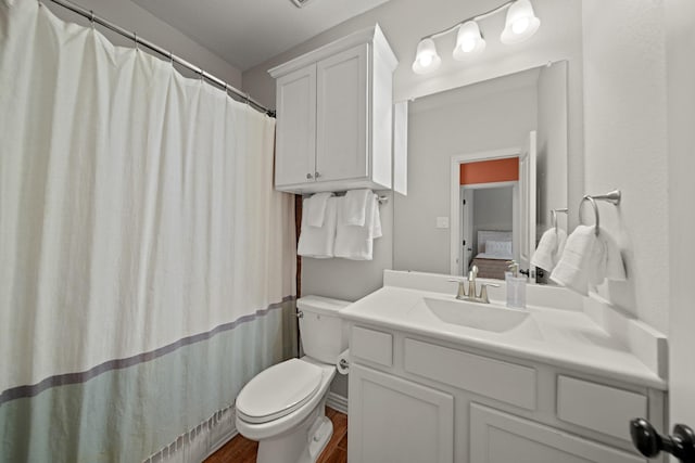 ensuite bathroom featuring vanity, toilet, wood finished floors, and connected bathroom