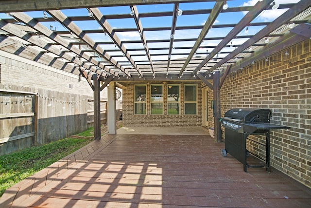 wooden deck featuring a grill, a pergola, and fence