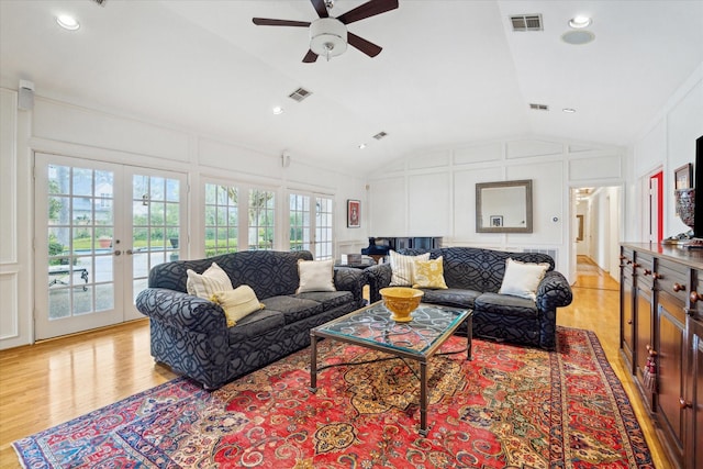 living room featuring light wood finished floors, visible vents, a decorative wall, and ceiling fan