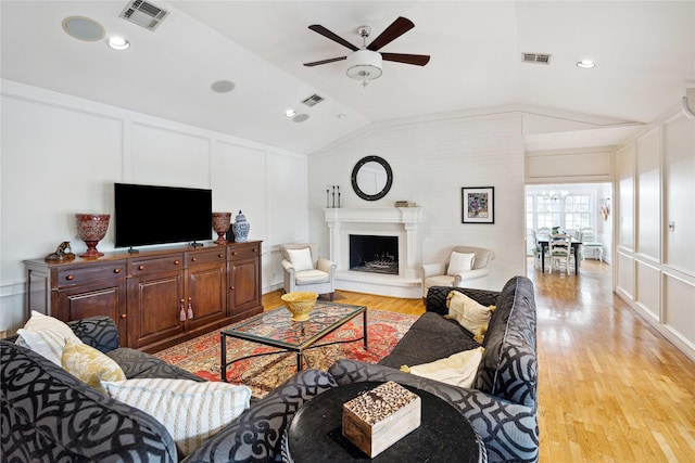 living room featuring lofted ceiling, a decorative wall, and visible vents