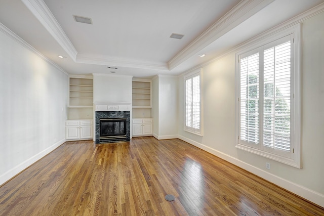 unfurnished living room featuring a tray ceiling, baseboards, a healthy amount of sunlight, and wood finished floors