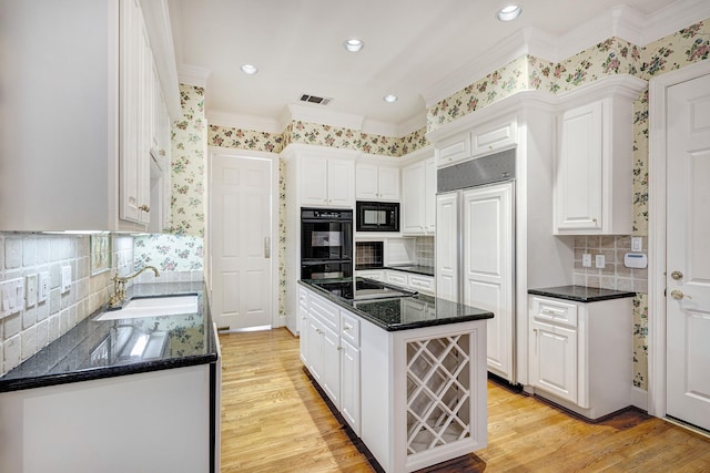 kitchen with a center island, light wood-type flooring, white cabinets, black appliances, and a sink