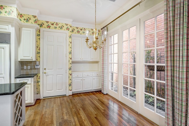 unfurnished dining area with a chandelier, light wood-style flooring, and crown molding