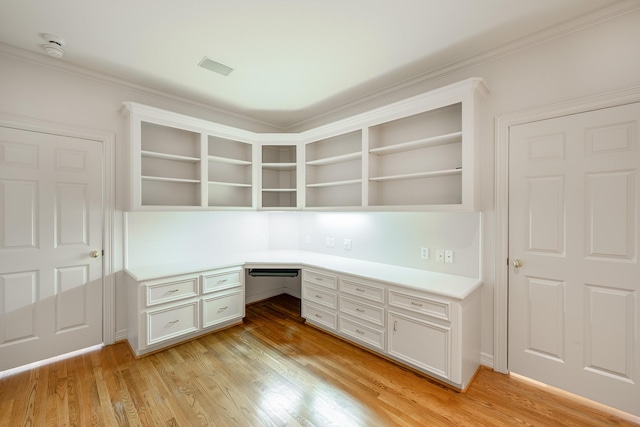 unfurnished office with light wood-type flooring, visible vents, and built in desk