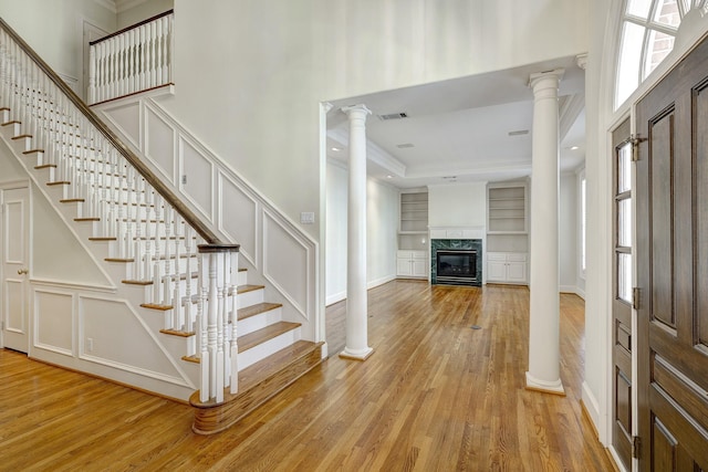 foyer featuring visible vents, stairway, light wood-type flooring, decorative columns, and a decorative wall