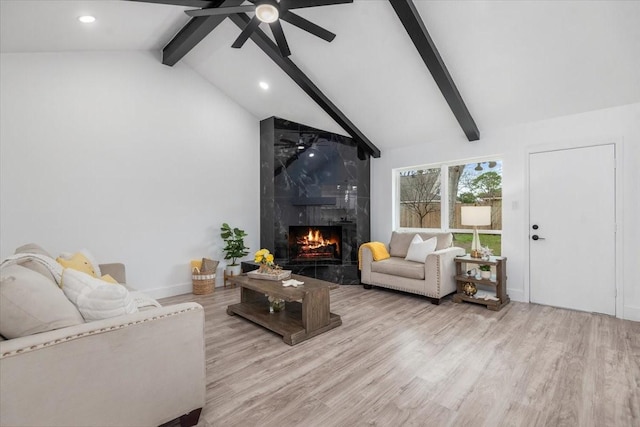living room featuring ceiling fan, beam ceiling, wood finished floors, and a fireplace