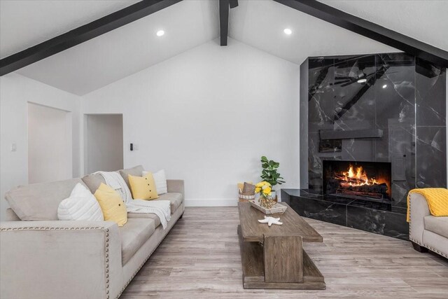 living room with lofted ceiling with beams, wood finished floors, recessed lighting, a premium fireplace, and baseboards