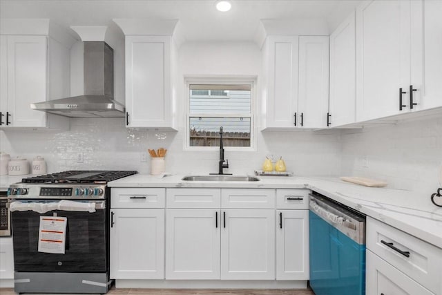 kitchen with stainless steel gas stove, a sink, white cabinetry, wall chimney range hood, and dishwasher