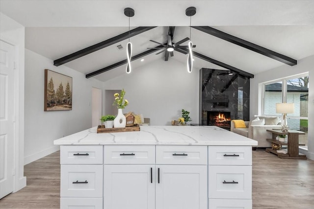 kitchen featuring a fireplace, open floor plan, vaulted ceiling with beams, and white cabinets