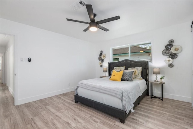 bedroom with visible vents, baseboards, wood finished floors, and a ceiling fan