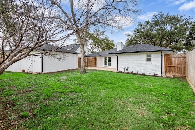 view of yard with a patio, a fenced backyard, and an outbuilding