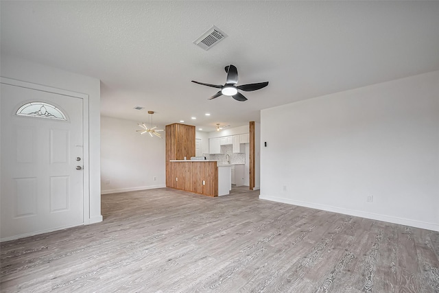 unfurnished living room featuring light wood-type flooring, baseboards, visible vents, and ceiling fan