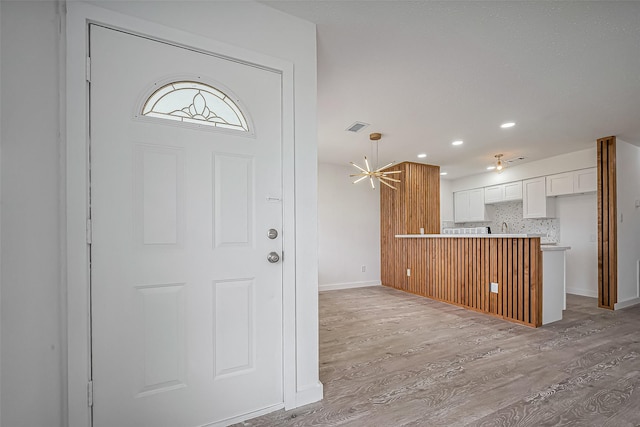 foyer entrance featuring recessed lighting, light wood-style floors, visible vents, and baseboards