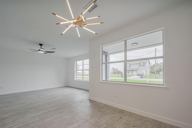 unfurnished room with wood finished floors, visible vents, and baseboards