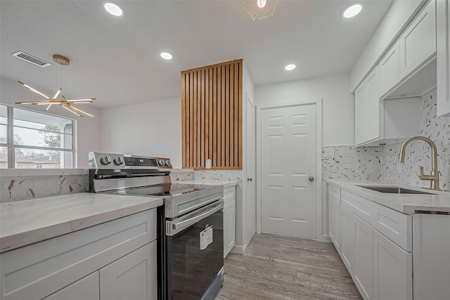 kitchen featuring visible vents, backsplash, stainless steel electric stove, white cabinetry, and a sink