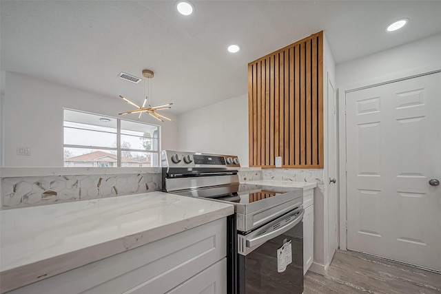 kitchen featuring electric range, white cabinetry, recessed lighting, light stone countertops, and a chandelier