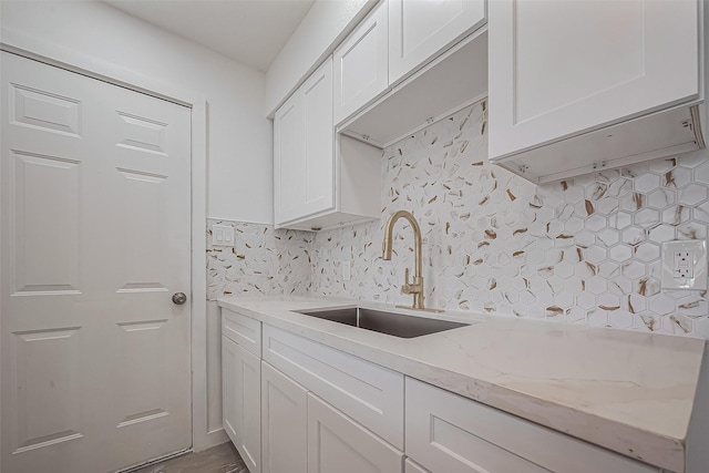 kitchen with white cabinets, light stone counters, tasteful backsplash, and a sink