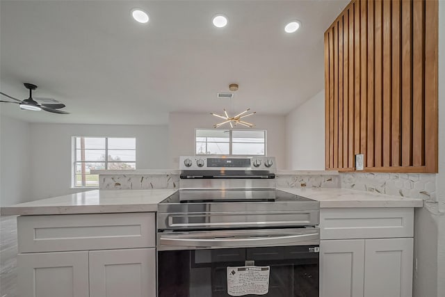 kitchen featuring visible vents, ceiling fan with notable chandelier, electric stove, recessed lighting, and light stone countertops