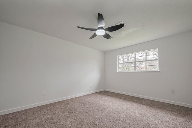 carpeted spare room featuring baseboards and a ceiling fan