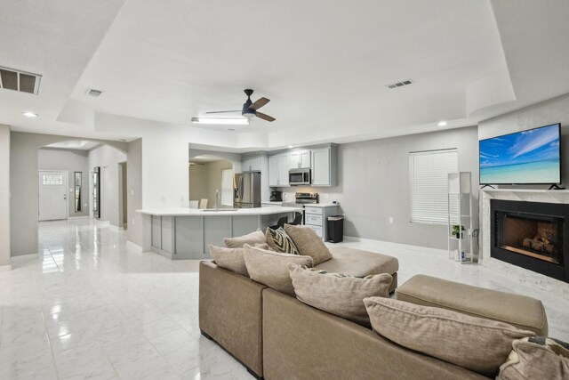298 County Road 3545, Cleveland, TX 77327 - living area with arched walkways, a fireplace, light marble finish floors, ceiling fan, and baseboards