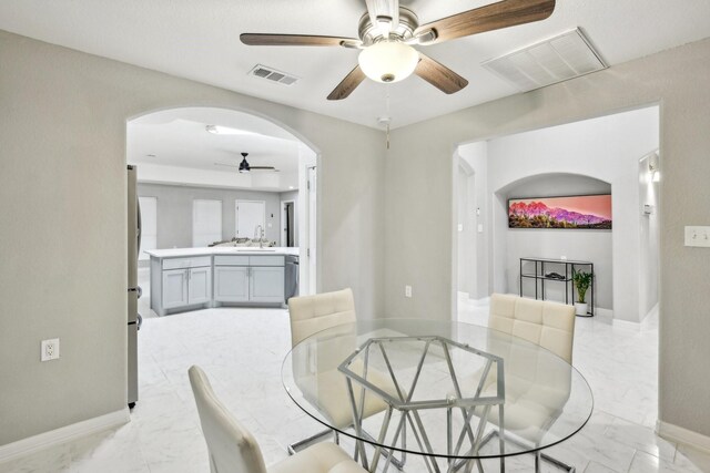 298 County Road 3545, Cleveland, TX 77327 - dining space featuring ceiling fan, arched walkways, light marble finish flooring, and baseboards