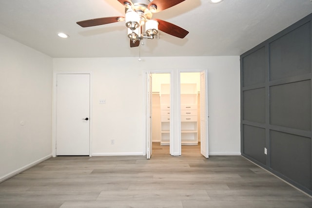 unfurnished bedroom with baseboards, light wood finished floors, recessed lighting, ceiling fan, and two closets