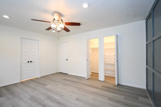 unfurnished bedroom with baseboards, light wood-style flooring, recessed lighting, ceiling fan, and two closets