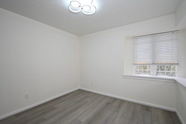 unfurnished room featuring wood finished floors, baseboards, and a textured ceiling