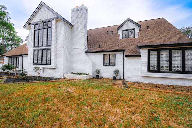 view of home's exterior featuring brick siding, a lawn, a chimney, and a shingled roof