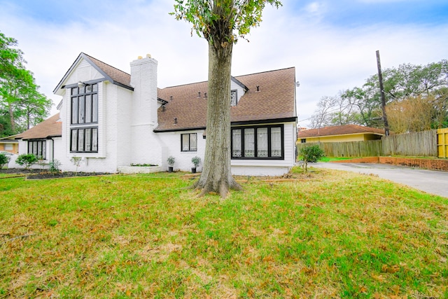 rear view of property featuring a lawn, a chimney, and fence