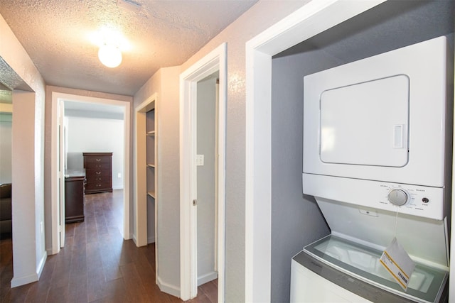 laundry room with stacked washer and dryer, a textured ceiling, dark wood finished floors, baseboards, and laundry area