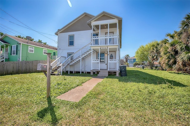 rear view of property featuring stairs, a yard, and fence