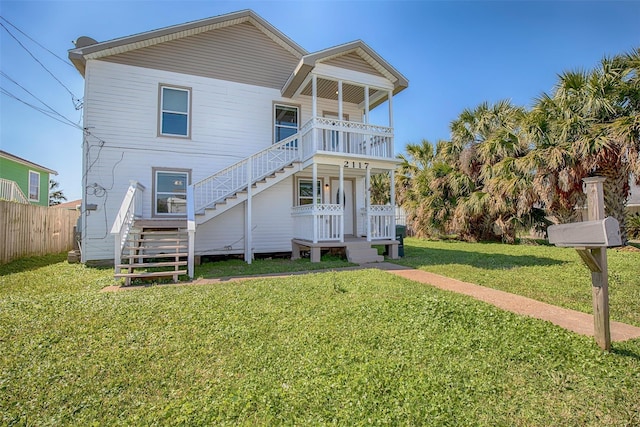 rear view of property with a yard, fence, and stairway