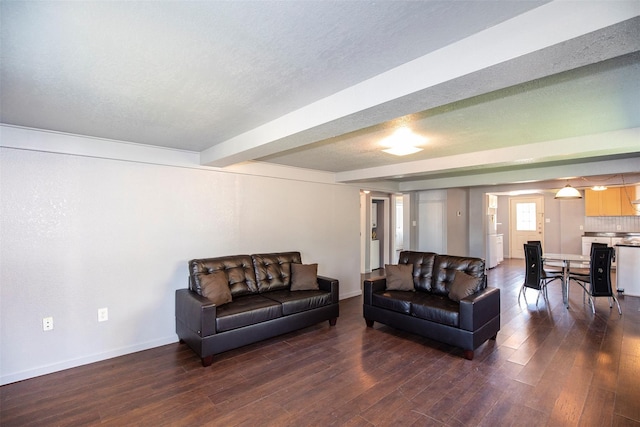living area featuring beam ceiling, baseboards, dark wood-style flooring, and a textured ceiling