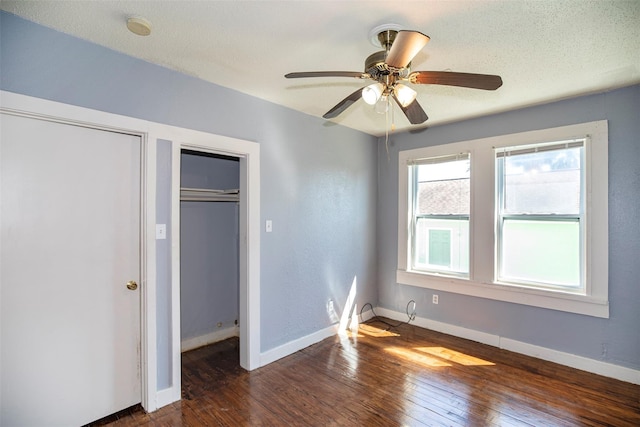 unfurnished bedroom featuring a textured ceiling, baseboards, and dark wood-style flooring