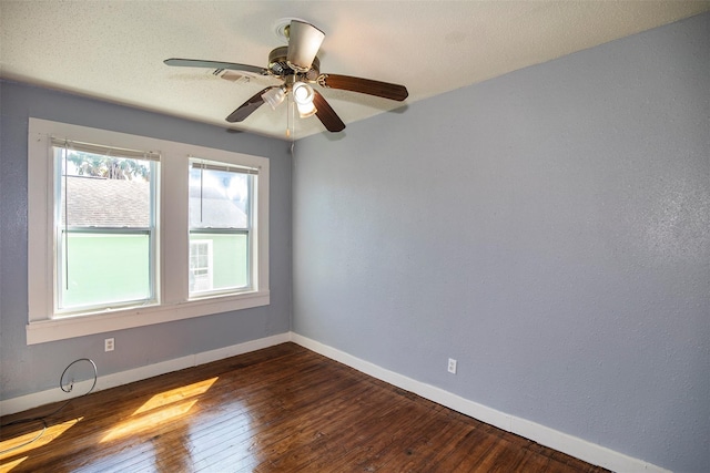 spare room with baseboards, dark wood-type flooring, ceiling fan, and a textured ceiling