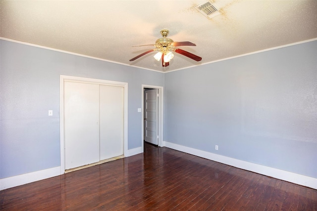 unfurnished bedroom with visible vents, wood finished floors, a closet, crown molding, and baseboards